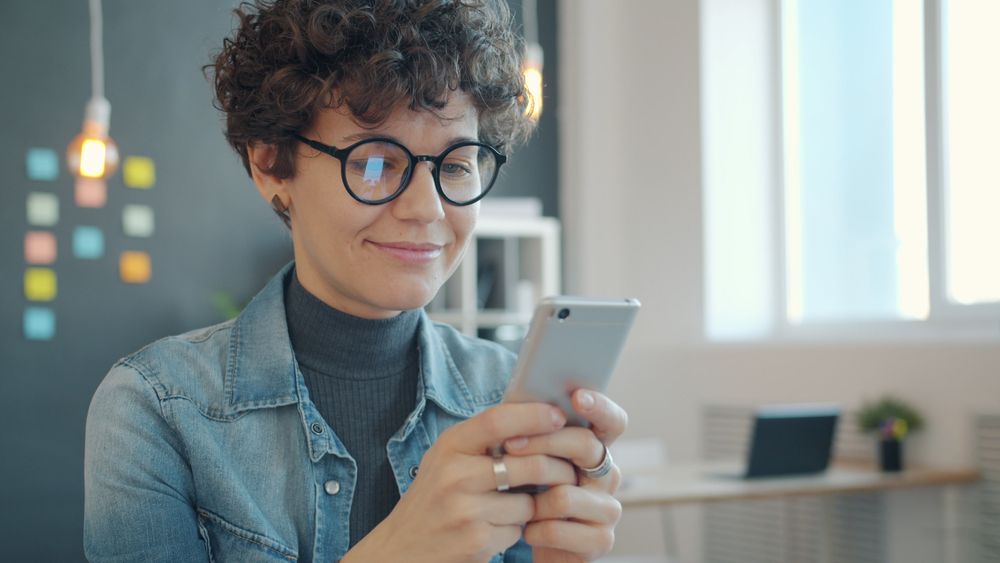 Woman smiling while using her smartphone